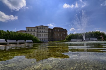 Obraz premium Venaria reale, Piedmont region, Italy. June 2017. The facade of the palace, on the side of the gardens, is reflected on the fountain's water mirror. Tourists explore the magnificent park.