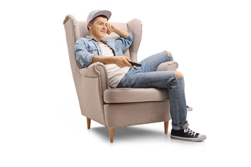 Teenage boy seated in an armchair watching television