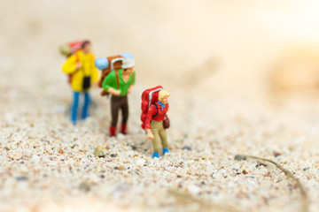 Fototapeta na wymiar Miniature people: travelers with backpack walking on the beach. Image use for travel, vacation concept.