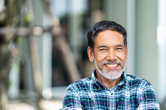 Portrait of happy mature man with white, grey stylish short beard looking at camera outdoor. Casual lifestyle of retired hispanic people or adult asian man smile with confident at coffee shop cafe.
