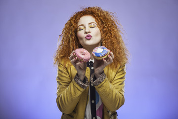 Young woman eating donut on blue background