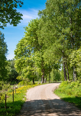 Fototapeta na wymiar Scenic countryside landscape with curvy road and fence at sunny summer day at Finland