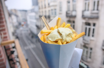Belgian fries with mayonnaise on blurred Brussels street
