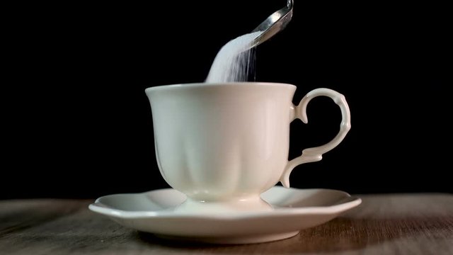 adding full teaspoon of sugar into tea cup drink , blood sugar of diabetes problems and sweet addiction , unhealthy eating habits concept