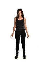full length portrait of brunette girl wearing black singlet, jeans jeans and boots. standing pose, isolated on white studio background.