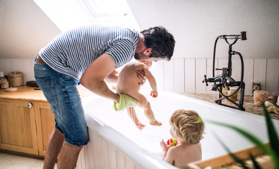 Father washing two toddlers in the bathroom at home.