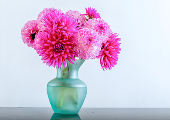 A mixture of pink dahlias in a turquoise vase.