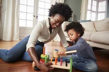 Mother And Young Son Playing With Wooden Toy At Home