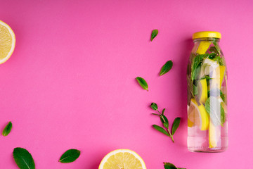 Detox fruit infused water, citrus fruits and mint leaves on pink background. Flat lay summer...