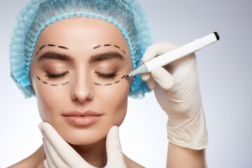 Hands in white gloves drawing lines on model's face