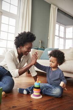 Mother Giving Son High Five As They Play With Toy At Home