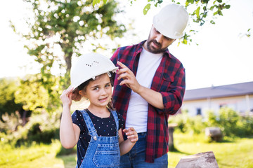 Father with a small daughter having fun with helmets in garden. Spring nature.