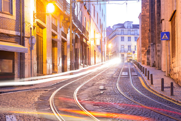 Cozy empty street with tram tracks and light tracks in Alfama, the oldest district of the Old Town in the morning, Lisbon, Portugal