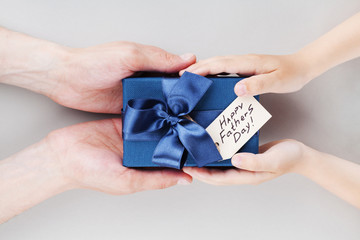 Son gives daddy present or gift box with tag on Happy fathers day. Holiday concept top view.