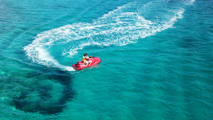 Aerial bird's eye view of jet ski cruising in high speed in turquoise clear water sea