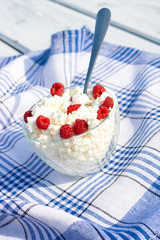 Milk and glass bowl with soft cheese and raspberry in summer