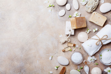 Spa setting from body care and beauty products with flowers on stone background top view. Flat lay.