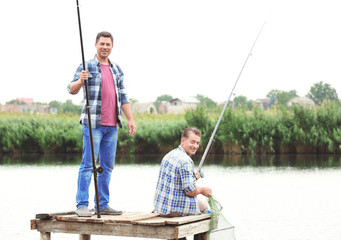 Two men fishing from pier on river