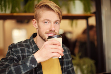 Portrait of trendy hipster drinking coffee in cafe