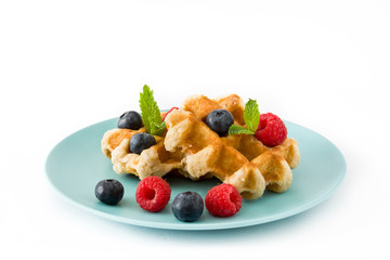 Traditional belgian waffles with blueberries and raspberries, isolated on white background. 