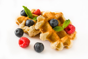 Traditional belgian waffles with blueberries and raspberries, isolated on white background. 