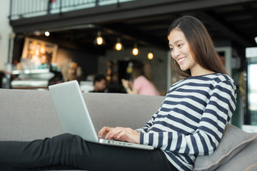 Asian woman using notebook on sofa at coffee shop,Independent work concept of the new generation