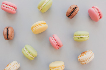 delicious colorful macaroons on trendy pastel gray paper flat lay. tasty pink, yellow, green and brown macaroons pattern. space for text. candy for party. yummy background