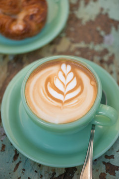 Fresh latte with tulip design in milk foam and pastry