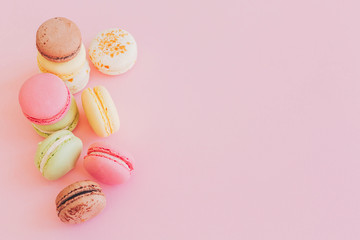 stylish colorful macaroons on trendy pink paper, flat lay. space for text. modern food photography concept. tasty pink, yellow, green, white, brown macarons. yummy background