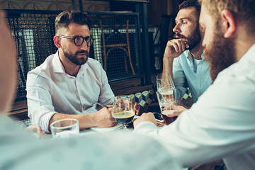 Young cheerful people smile and gesture while relaxing in pub.