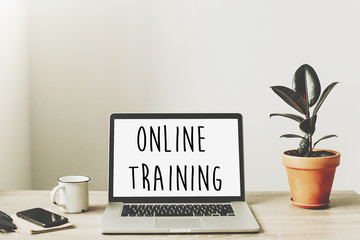 online training text on laptop screen on wooden desktop with phone, notebook, coffee and plant. business workspace. internet Education concept. e-learning.