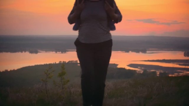 Summer evening ,mom and the child show the plane with their hands. Mother and her little son have fun against the scarlet sunset .Mother holds child on shoulders they run and laugh