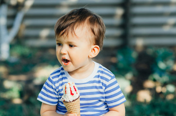 a child in a t-shirt on a bench eating ice cream in the summer, very hot and tasty