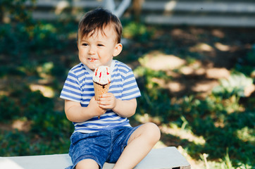 a child in a t-shirt on a bench eating ice cream in the summer, very hot and tasty