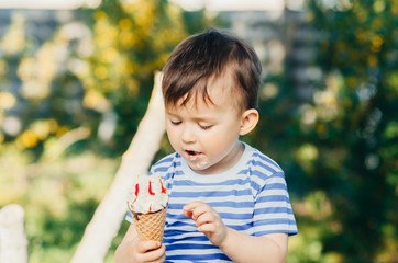 a child in a t-shirt on a bench eating ice cream in the summer, very hot and tasty