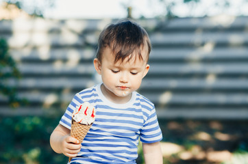 a child in a t-shirt on a bench eating ice cream in the summer, very hot and tasty