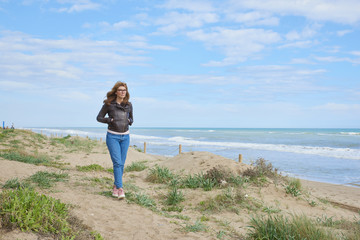 Woman standing at the beach in casual jeans and leather jacket