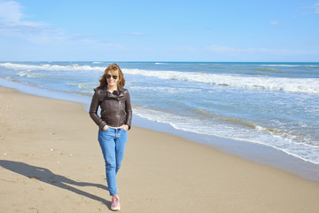 Woman standing at the beach in casual jeans and leather jacket