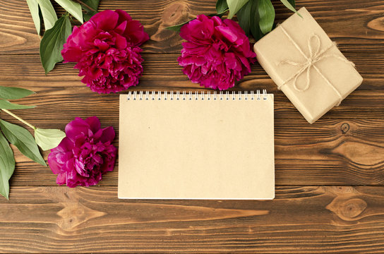 peonies, empty notepad craft paper sheet on wooden background