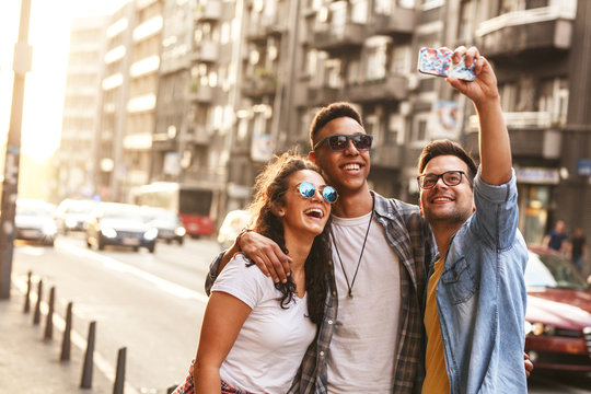 Group of friends hangout  at the city street.They embrace each other and doing selfie.