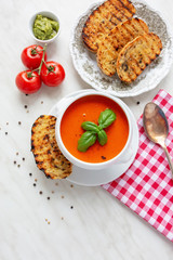 Fresh homemade tomato soup with fresh grilled Italian bread. Perfect lunch or dinner. On white table. Natural light, selective focus.