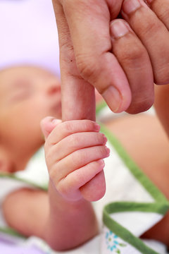 Newborn baby gripping mother finger
