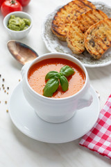 Fresh homemade tomato soup with fresh grilled Italian bread. Perfect lunch or dinner. On white table. Natural light, selective focus.