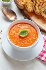 Fresh homemade tomato soup with fresh grilled Italian bread. Perfect lunch or dinner. On white table. Natural light, selective focus.