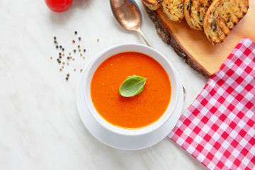 Fresh homemade tomato soup with fresh grilled Italian bread. Perfect lunch or dinner. On white table. Natural light, selective focus.