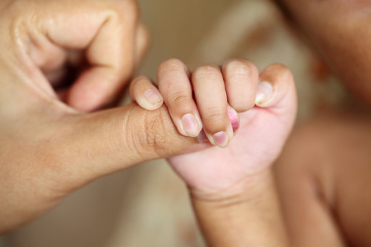 Newborn baby gripping mother finger