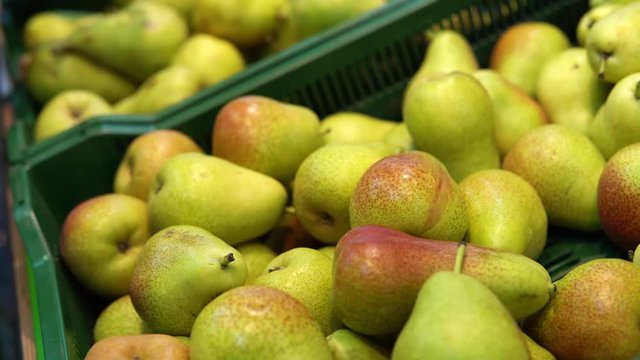 Someone selects pears in the supermarket. Female hand chooses green fruits in the vegetable department at the grocery store.