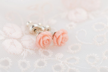 Fototapeta na wymiar Cute pink little roses earring studs on lace