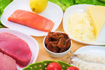 Raw appetizing fillet of tuna on a table with a yard of Greek salad with salmon and lemon cucumbers and tomatoes as well as cheese. The concept of a delicious and healthy home-made meal