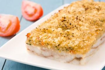 White fish casserole with cheese on blue wooden background.